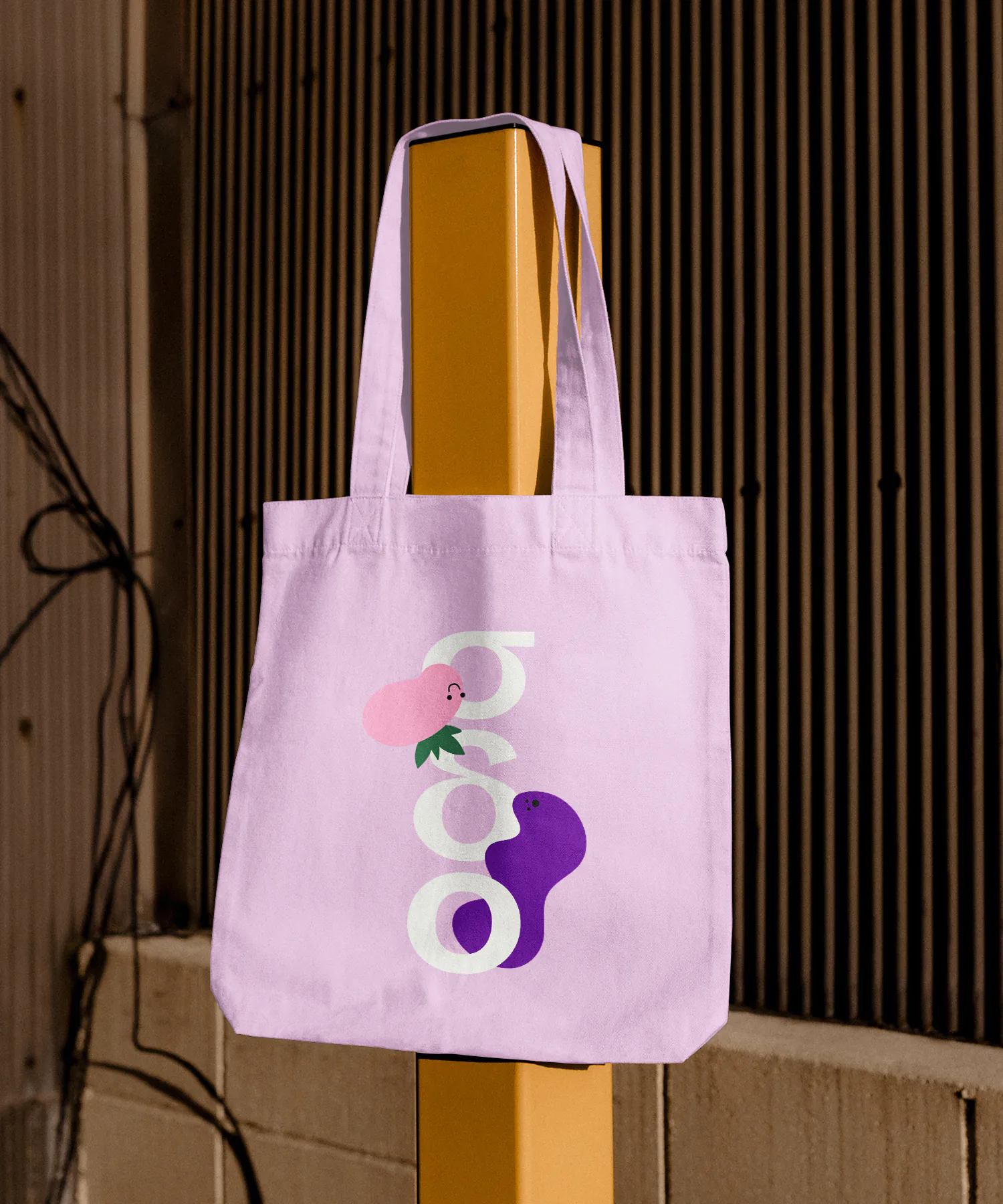 Tote bag hanging from a wooden pole, showing abstract illustrations for Greek peer mediation at school group.