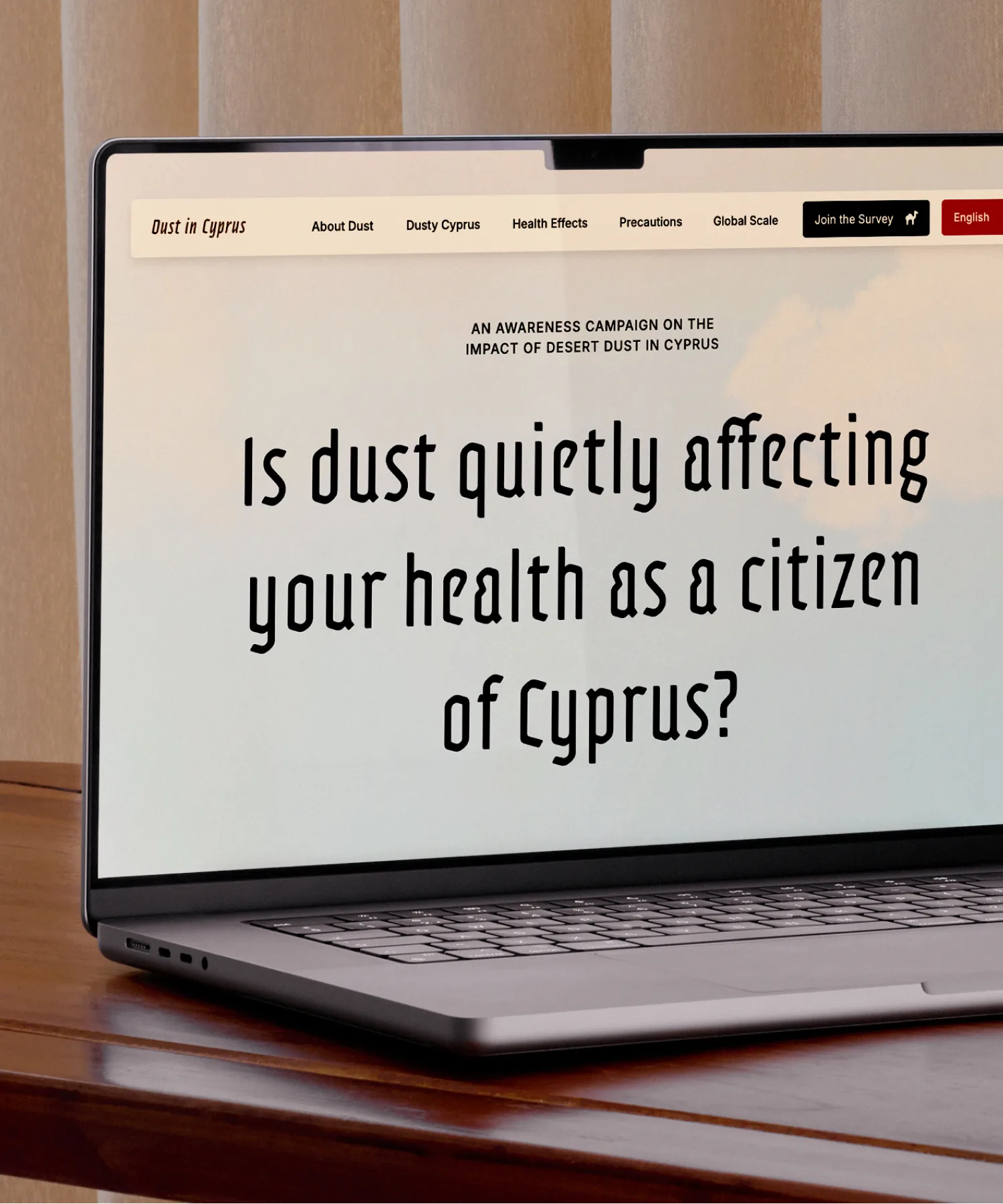 Dust in Cyprus website landing page, previewed in a laptop, which is placed on top of the table.