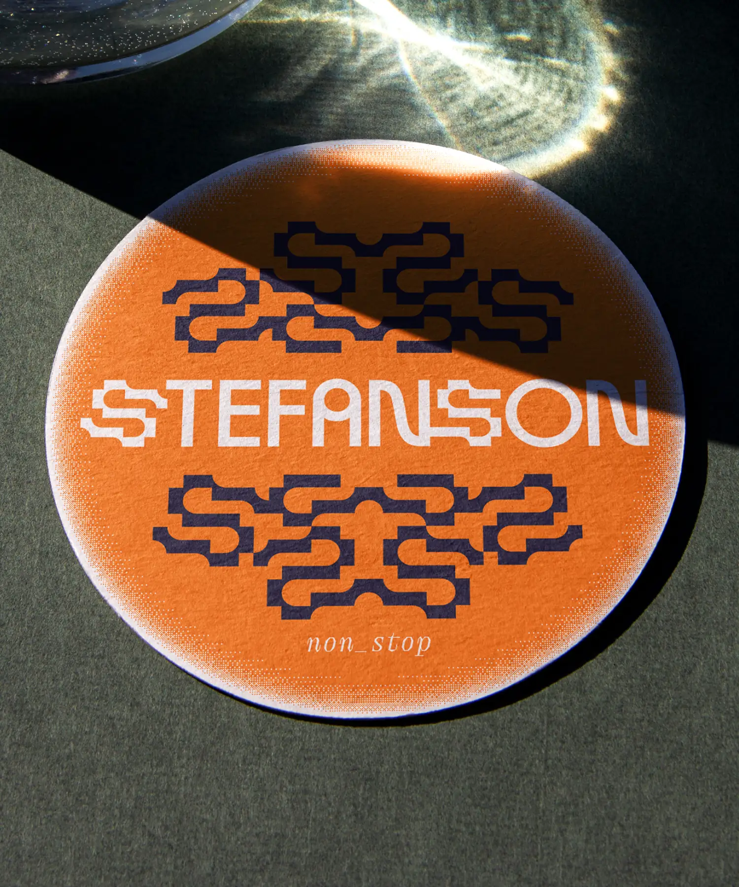 Branded Stefanson coaster on the table, with a light reflection dropping on it.