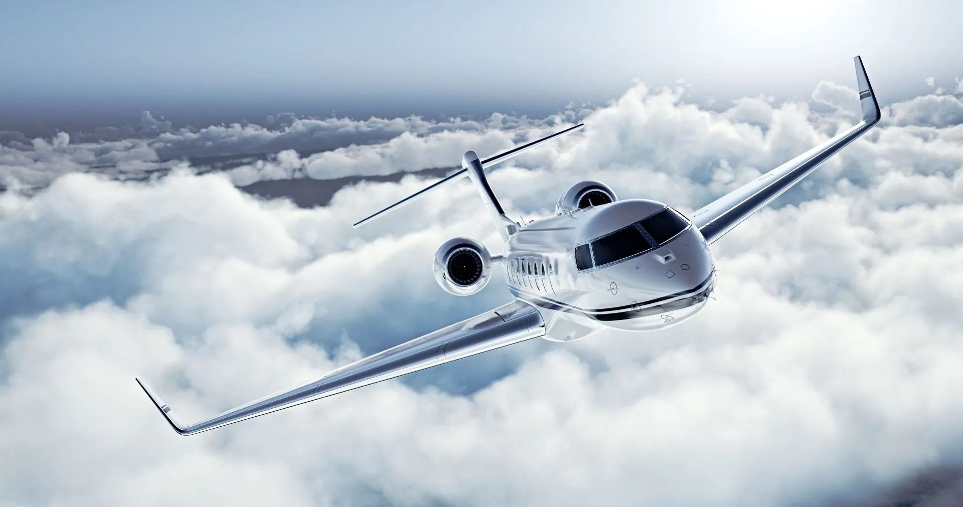White private jet flying above white clouds in a clear blue sky, viewed from the front.