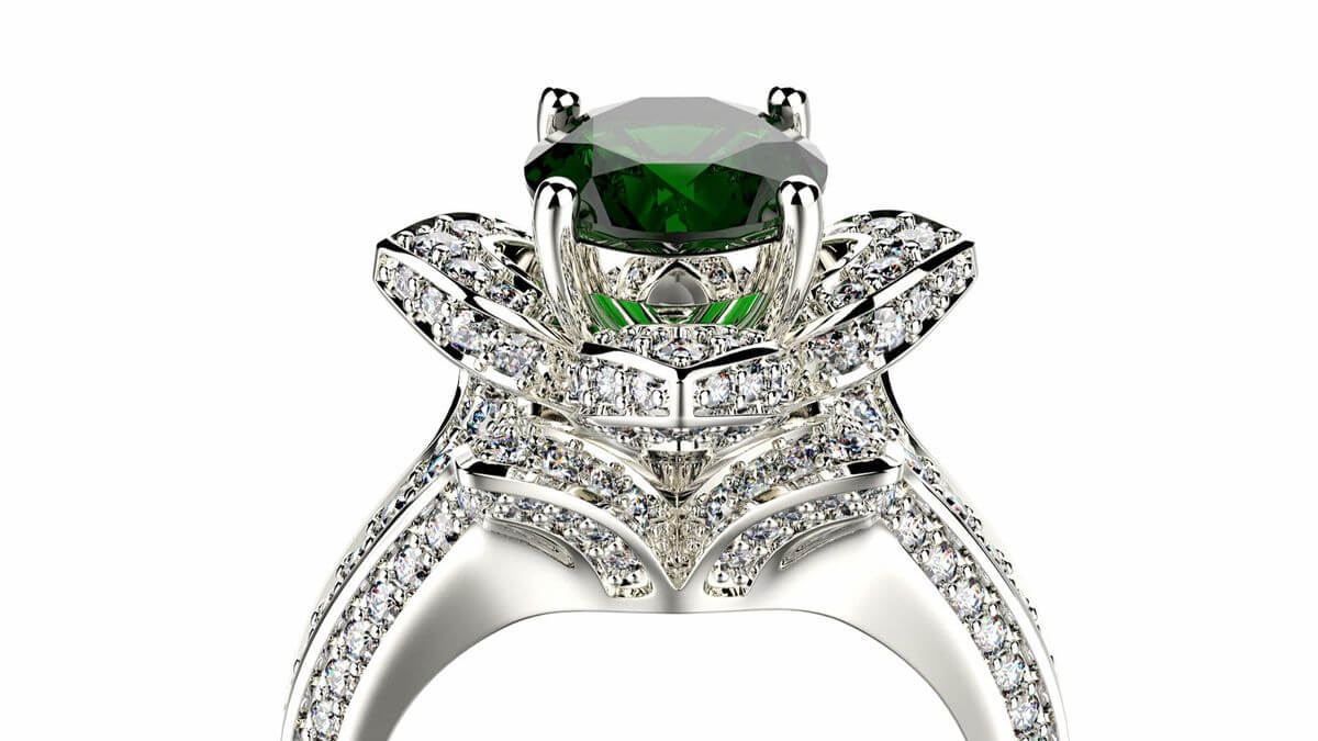 Close-up of a silver ring with a large green gemstone surrounded by intricate diamond-studded design.
