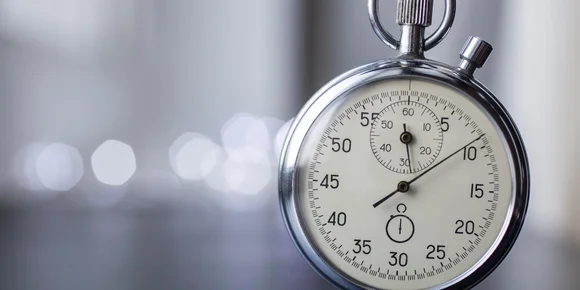 Primo piano di un cronometro argentato con quadrante bianco che mostra secondi e minuti su uno sfondo sfocato.