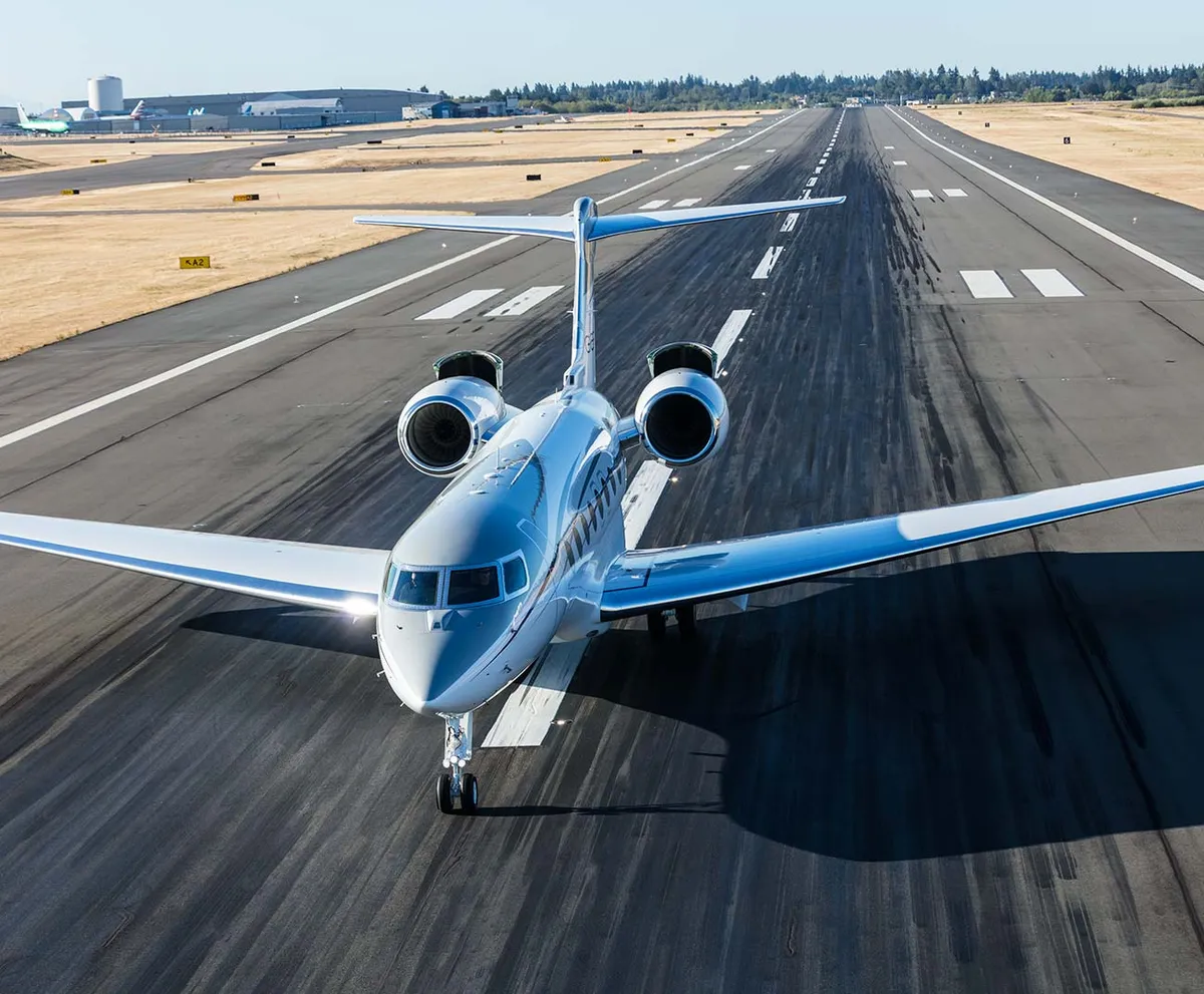 White private jet airplane on a runway during daytime with clear sky.