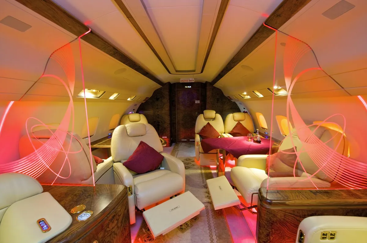 Luxurious private jet interior with beige leather seats, red cushions, a table with a purple cloth, and mood lighting.