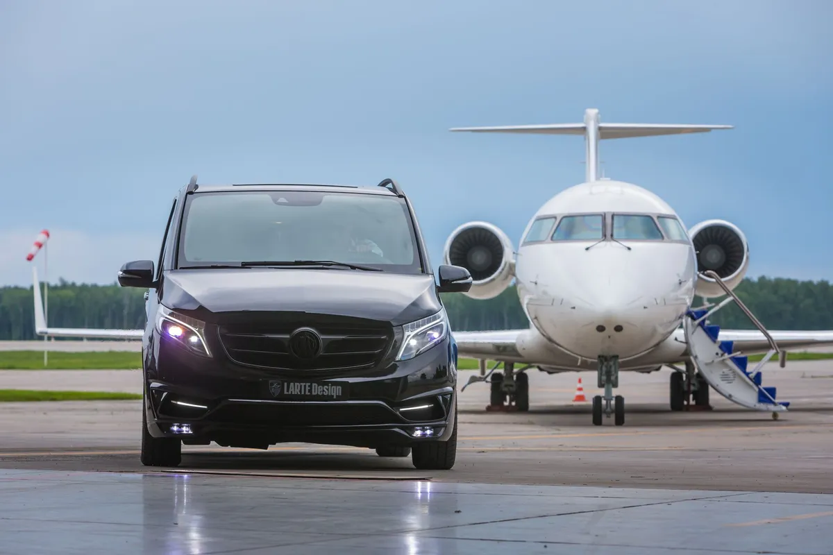 Black luxury van with LARTE Design badge parked in front of a private white jet airplane on an airport tarmac.