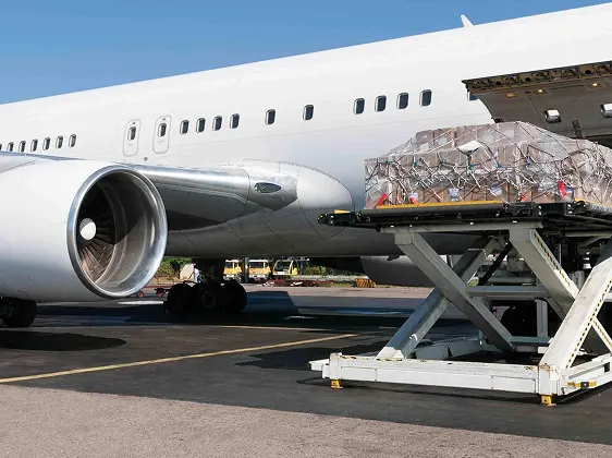 a large commercial airplane being loaded with cargo on a tarmac under a clear blue sky