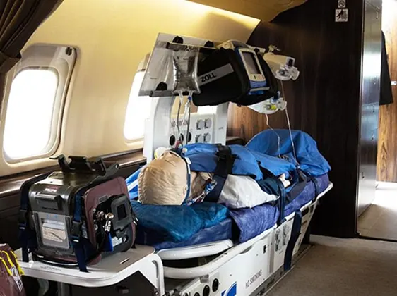Medical stretcher inside a private jet equipped with a mannequin patient and advanced medical equipment.