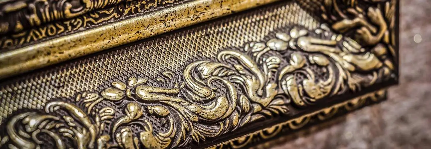 Gros plan d'un cadre décoratif en or et en bronze orné de motifs floraux et de volutes complexes.