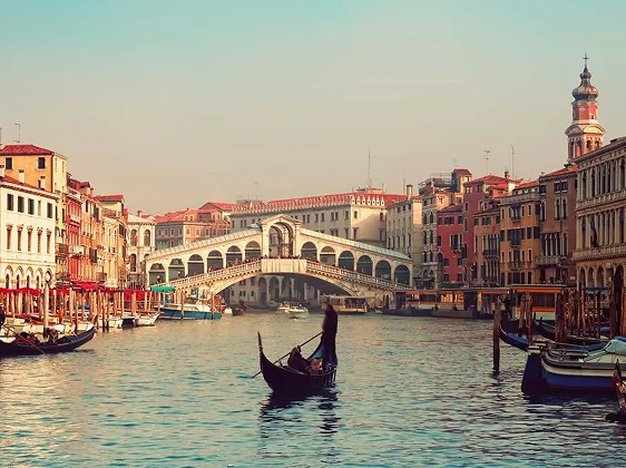 Venice Grand Canal with gondola and Rialto Bridge at sunset for romantic weekend getaway