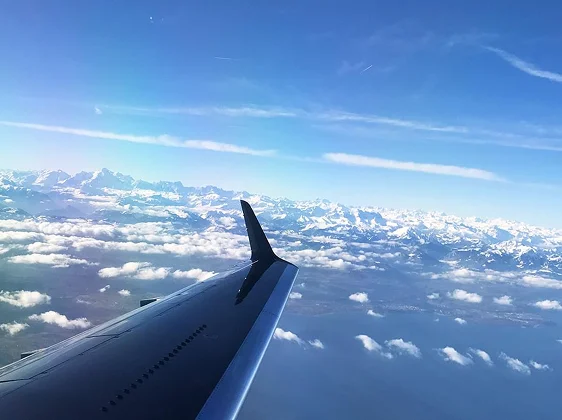 Aerial view of private jet wing flying above clouds during luxury travel adventure