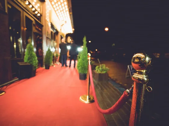 Red carpet entrance with velvet rope and stanchions leading to luxury venue for VIP events and celebrations