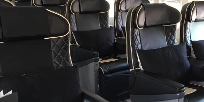 Przestronne wnętrze prywatnej kabiny odrzutowca z czarnymi skórzanymi siedzeniami do lotów czarterowych