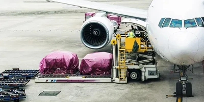 Fioletowe kontenery ładowane na samoloty komercyjne w celu czarteru frachtu lotniczego