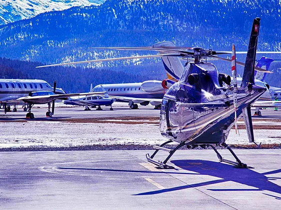 Helicopter and private jets at snowy mountain airport for last minute ski holiday charter