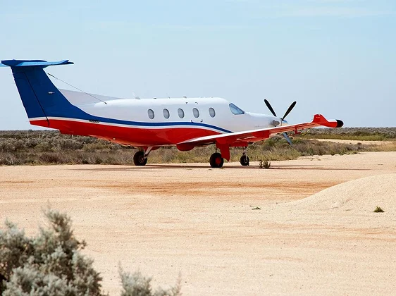 Red and white private jet on remote desert runway for emergency evacuation and repatriation service