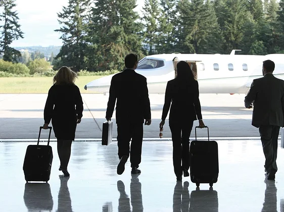 Silhouettes of four business professionals with luggage walking toward private jet for urgent corporate crisis meeting