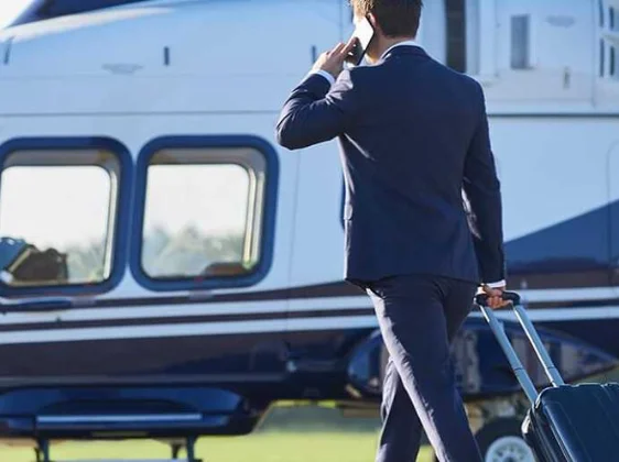 Business executive in suit boarding blue helicopter with luggage for corporate professional visit