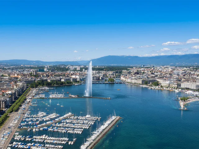 Vista aérea del lago Lemán con un gran chorro de agua de una fuente y muchos barcos atracados en el puerto deportivo.