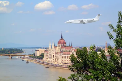 Ein Privatjet fliegt über das ungarische Parlamentsgebäude und die Donau in Budapest.