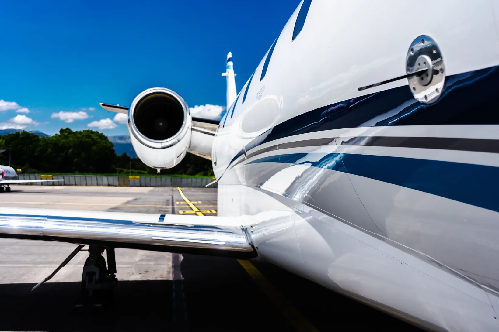 White and blue Cessna Citation XLS jet parked at airport tarmac, close-up side view showing engine and fuselage details.