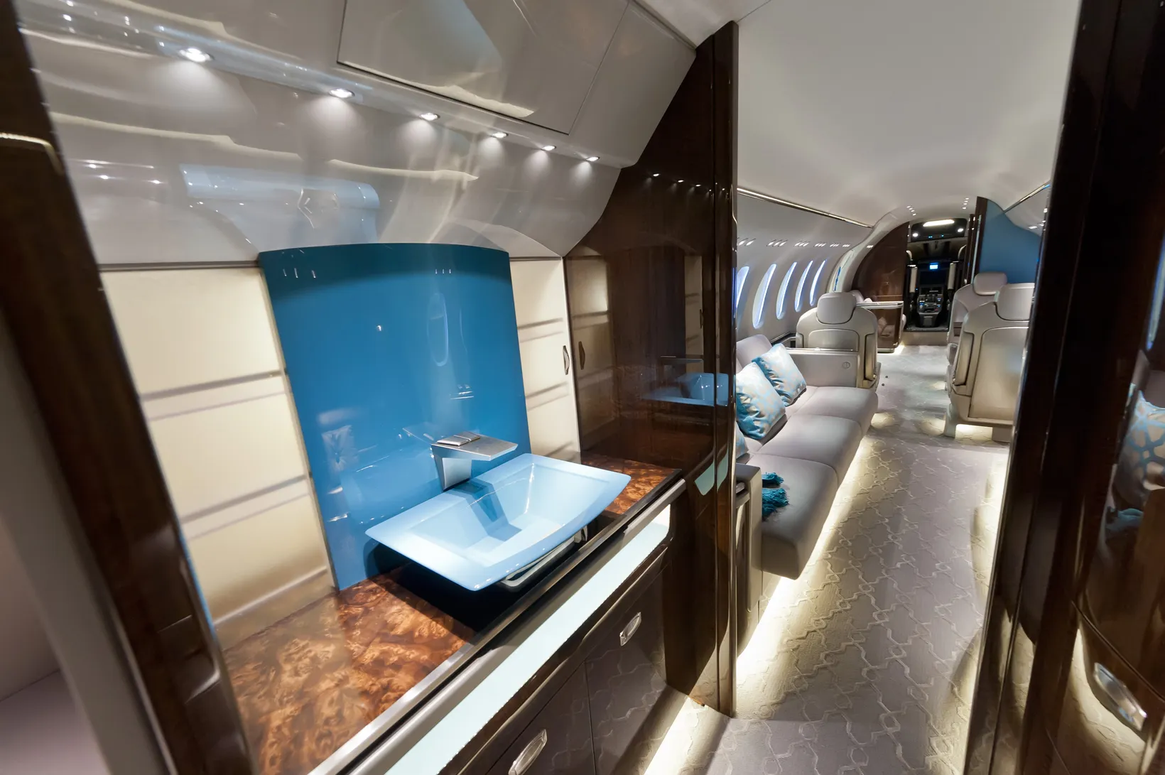 Interior cabin view of Cessna Citation Latitude private jet showing luxury seating, blue galley area, and spacious aisle i...
