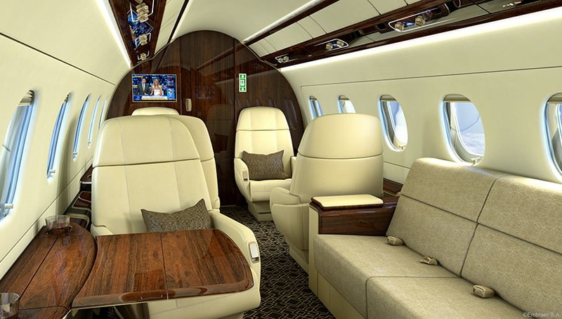 Embraer Legacy 500 cabin interior showing cream leather seats, wood accents, windows, and modern furnishings in a luxury p...
