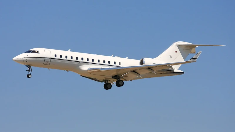 Bombardier Global 6000 in flight against clear blue sky, shown in profile view with landing gear deployed, displaying slee...