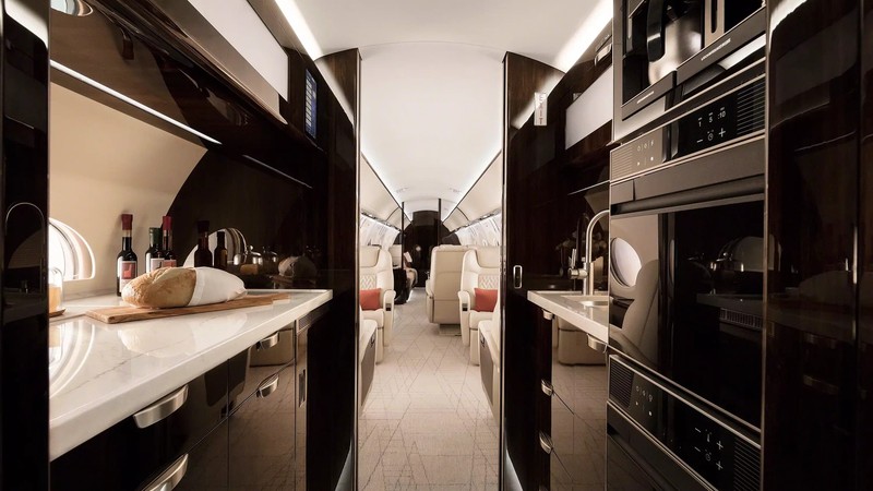 Gulfstream G600 galley interior showing dual kitchens with black cabinetry, marble countertops, stainless steel appliances...