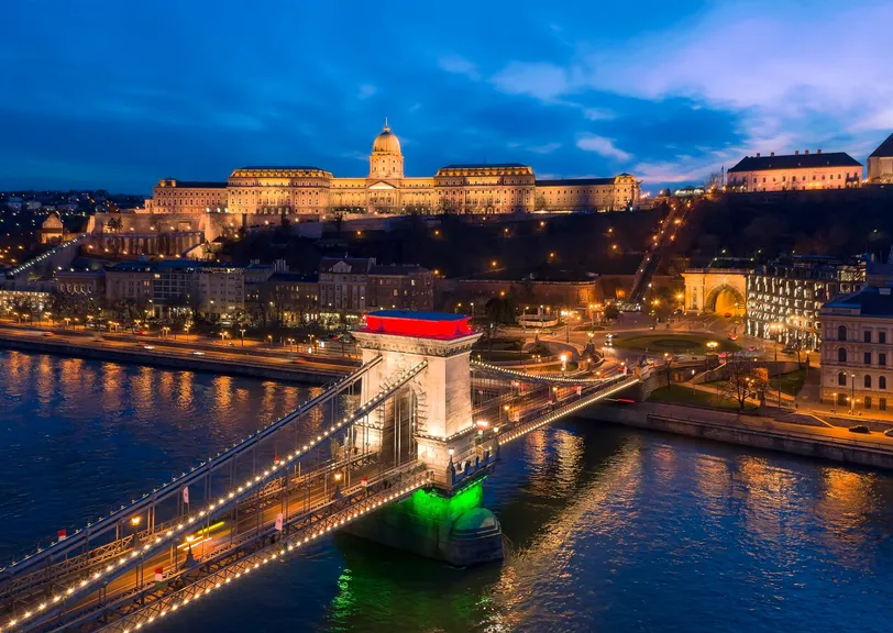 Die beleuchtete Széchenyi-Kettenbrücke in Budapest, Ungarn, wunderschön beleuchtet gegen den Nachthimmel, mit der Budaer Burg im Hintergrund.