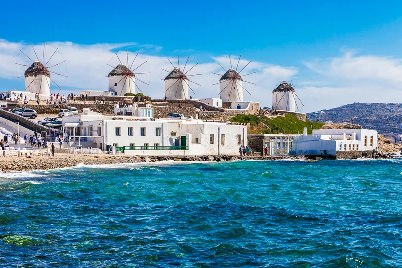 Mykonos híres szélmalmai, kilátással a vibráló kék Égei-tengerre, tökéletes luxus úti cél.