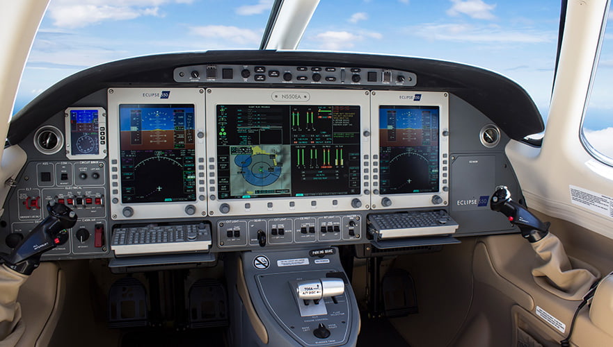 Eclipse 550 cockpit interior showing avionics displays, instrument panels, and controls with sky visible through windscreen.