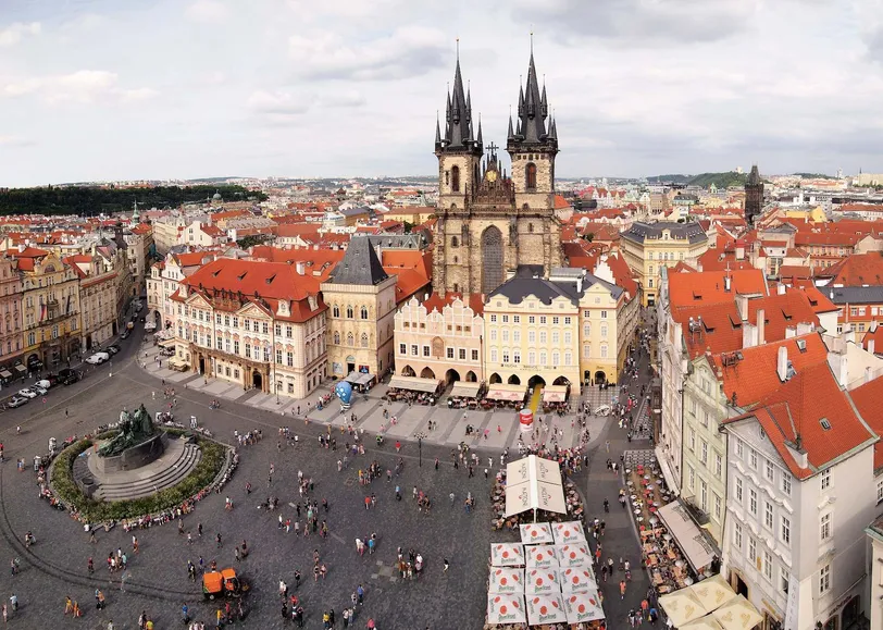Légi felvétel a prágai Óváros térről, amelyen az ikonikus Tyn-templom és a nyüzsgő tömeg élvezi a történelmi tér varázsát