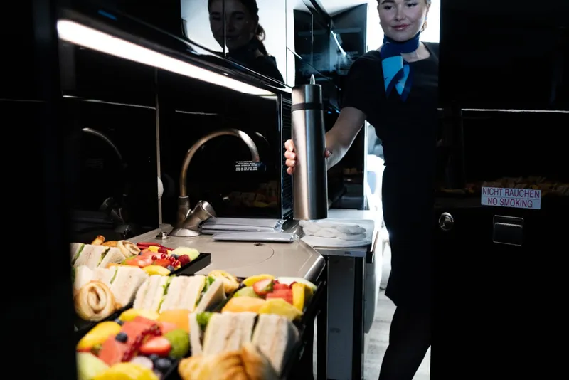 Un auxiliar de vuelo sirviendo un plato de catering en un jet privado