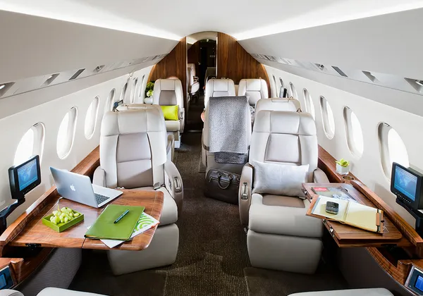 Luksusowa kabina prywatnego odrzutowca z kremowymi skórzanymi siedzeniami, drewnianymi stolikami i osobistymi ekranami
