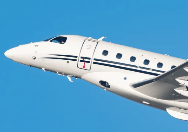 Zbliżenie nosa i kadłuba samolotu odrzutowego Embraer Praetor 600 na tle czystego, błękitnego nieba