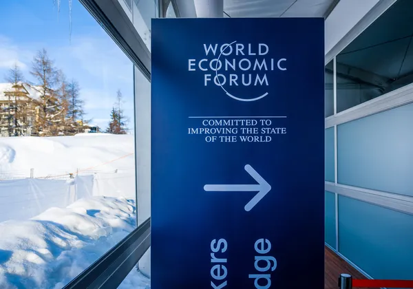 Znak wejścia na Światowe Forum Ekonomiczne z flagami powiewającymi nad chodnikiem