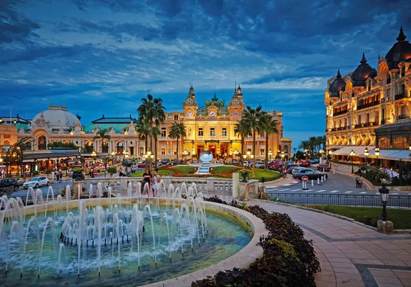 Kasyno Monte-Carlo i fontanna oświetlone o zmierzchu w Monako