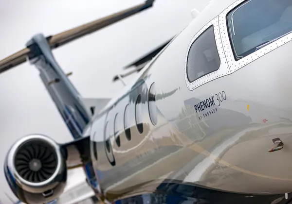 Samolot biznesowy Embraer Phenom 300 lecący nad linią brzegową