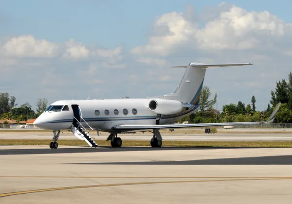 Prywatny odrzutowiec zaparkowany na płycie lotniska z otwartymi drzwiami i wysuniętymi schodami wejściowymi