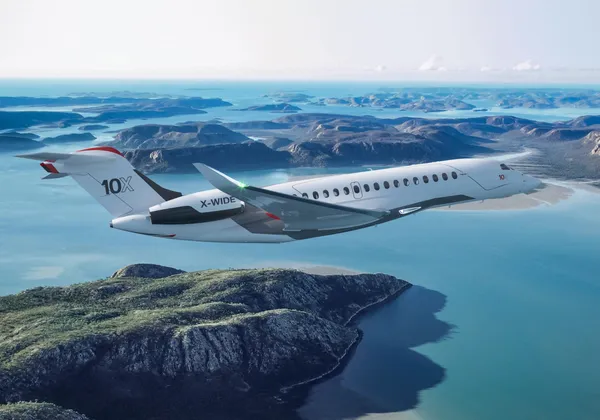 Samolot biznesowy Dassault Falcon 10X lecący nad skalistą linią brzegową i turkusowym morzem