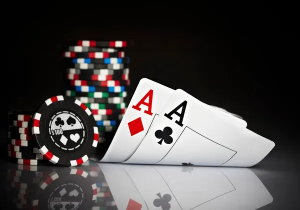 Dwa asy i żetony pokerowe na zielonym stole pokrytym suknem podczas turnieju w Las Vegas