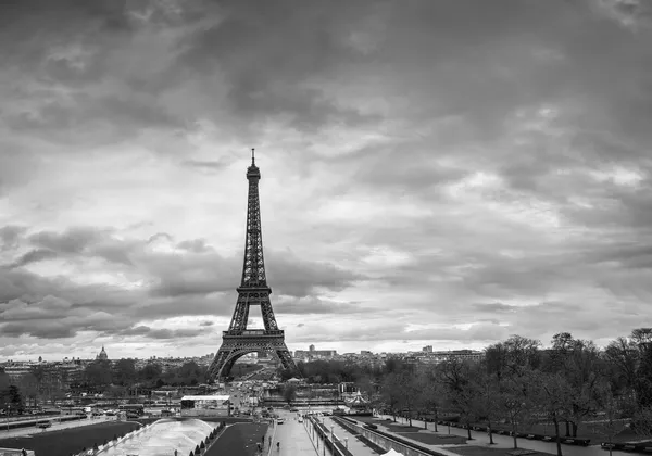 Czarno-białe zdjęcie Wieży Eiffla z dramatycznymi chmurami nad nią