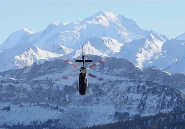 Śmigłowiec lecący w kierunku pokrytych śniegiem alpejskich gór zimą
