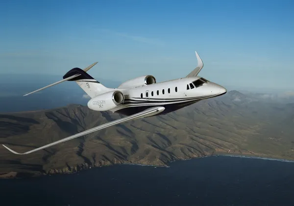 Ein Cessna Citation X Privatjet fliegt über eine Küstenberglandschaft
