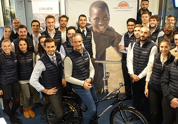 Zespół Lunajets pozuje z rowerem przed plakatem World Bicycle Relief