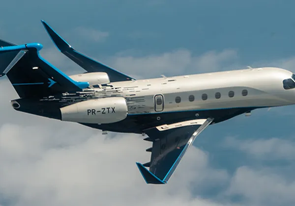Samolot odrzutowy Embraer Praetor 600 z niebieskimi końcówkami skrzydeł przechylający się nad chmury