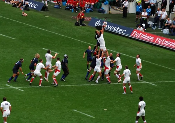 Rugby-Spieler kämpfen in einem Spiel mit Zuschauern und Werbebanden um einen Einwurf.