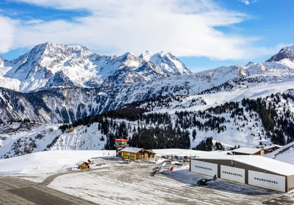 Zaśnieżony port lotniczy Courchevel z krótkim pasem startowym i hangarami wśród alpejskich gór