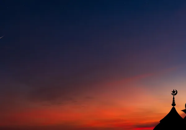 Złoty sierp księżyca i oświetlona sylwetka meczetu świętują Eid al-Fitr