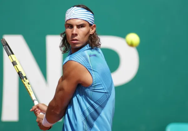 Profesjonalny tenisista uderzający bekhendem na korcie ziemnym